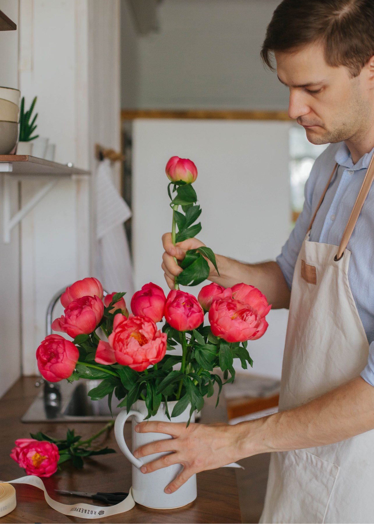 A florist arranging peonies in the workshop
